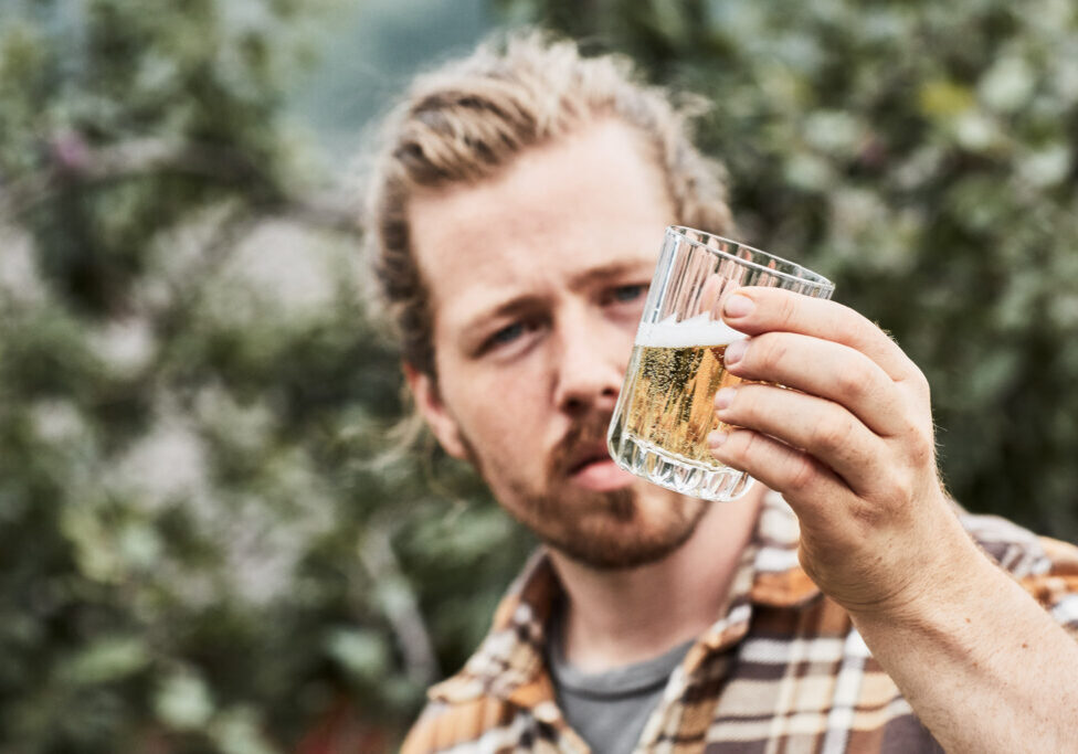 A man holding a glass containing a sparkling, yellow liquid.