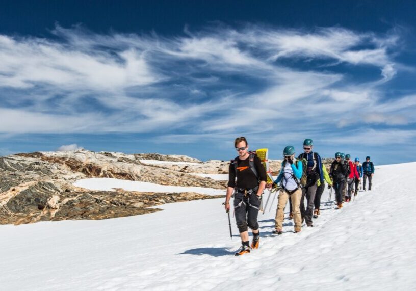 A group of people walking in a line on a glacier.