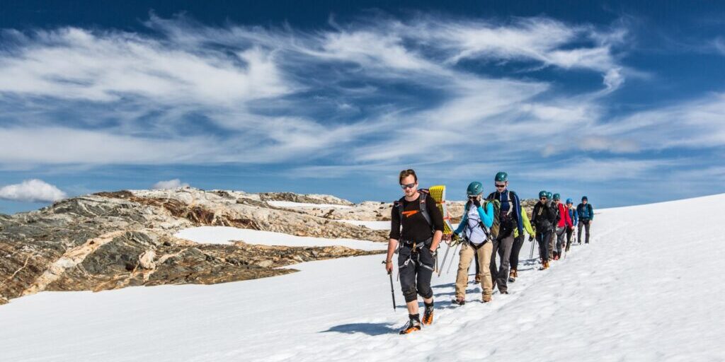 A group of people walking in a line on a glacier.