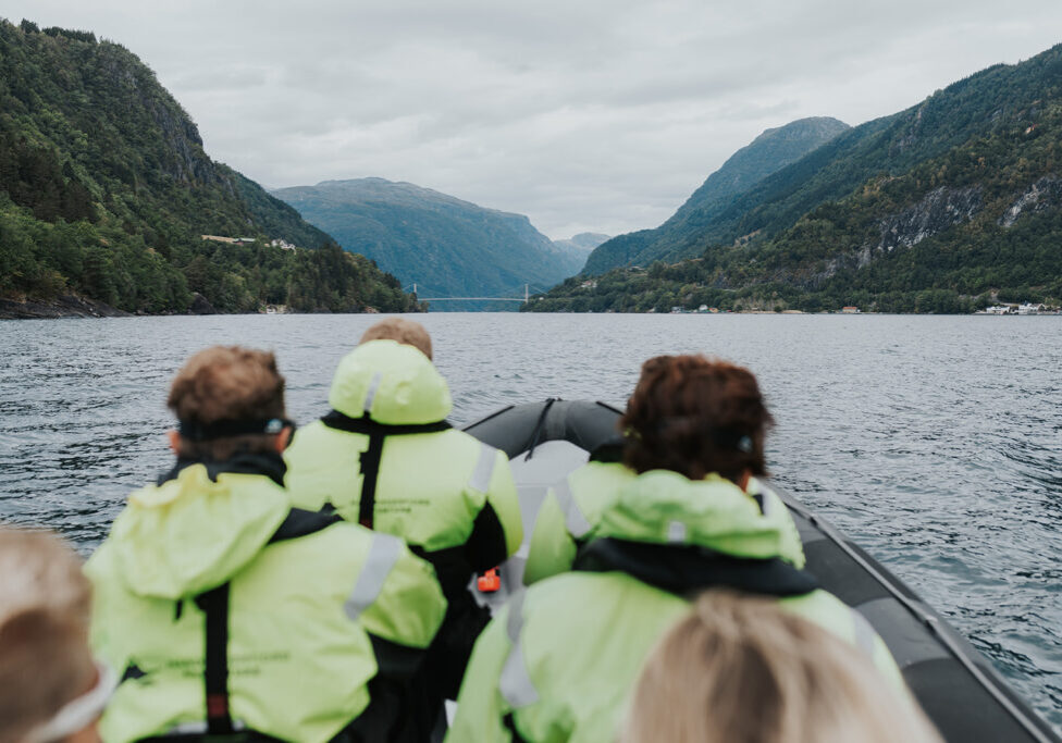 People in floatation suits on a RIB boat looking at a bridge.