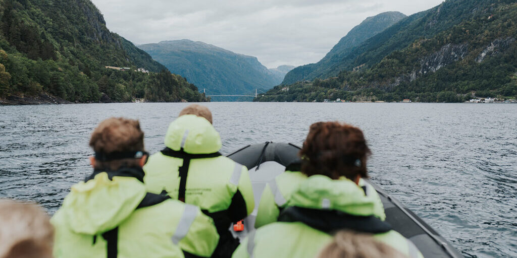 People in floatation suits on a RIB boat looking at a bridge.
