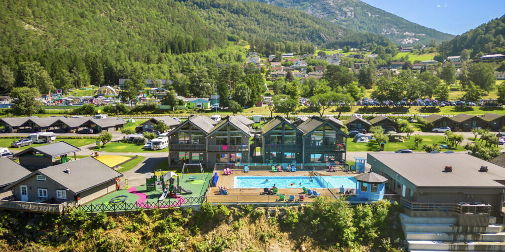 A holiday resort with swimming pool and mountains int he background.