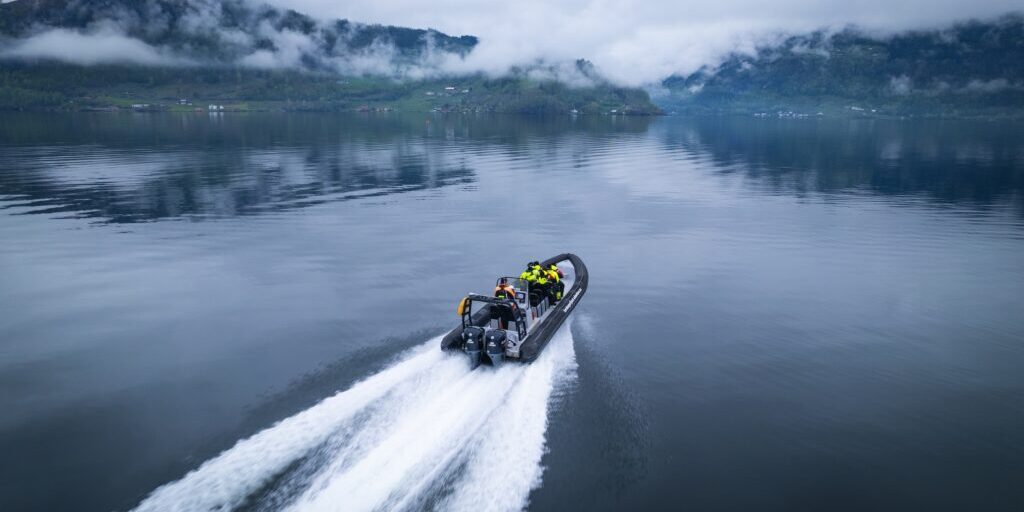 RIB boat cruising on a fjord on a cloudy day.
